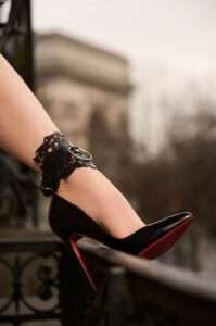 Un pied de femme portant un bracelet de cheville en cuir noir et des talons aiguille